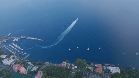 Aerial-footage-of-a-speedboat-taking-off-from-the-coast-off-of-the-town-of-Sorrento,-Italy-in-the-morning