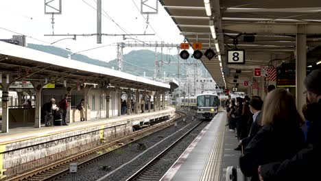 Pendler-Warten-Auf-Dem-Bahnsteig-Des-Bahnhofs-Kyoto,-Während-Sich-Der-Zug-Der-Jr.-Nara-Linie-In-Zeitlupe-Nähert