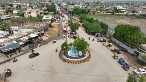 Aerial-Main-roundabout-in-Badin-city-centre-with-light-traffic,-Sindh-rural-Pakistan
