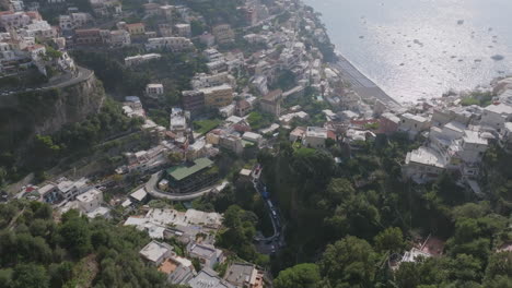 Aerial-footage-flying-towards-the-town-of-Positano,-Italy-on-the-Amalfi-Coast,-showing-traffic-on-the-mountainous-roads