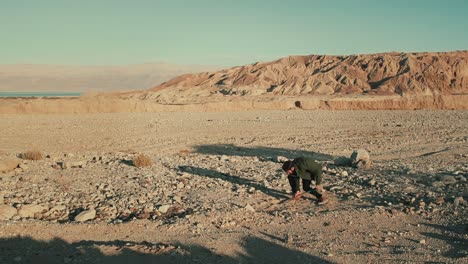 Weitwinkelaufnahme-Eines-Mannes,-Der-Mit-Einem-Spaten-Ein-Loch-In-Der-Trockenen-Judäischen-Wüste-Gräbt