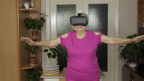 Grandmother-in-virtual-headset-glasses-watching-video-in-VR-helmet-and-training-workout-at-home