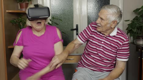 Grandfather-scares-grandmother-with-VR-headset-while-she-watching-scary-virtual-reality-video-game