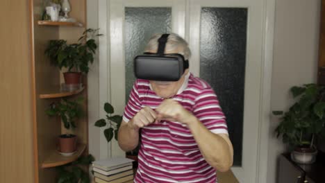 Grandmother-in-virtual-headset-glasses-watching-video-in-VR-helmet-training-box,-shows-fist-fight