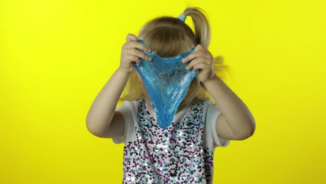 Kid-playing-with-hand-made-toy-slime.-Child-having-fun-making-turquoise-slime.-Yellow-background