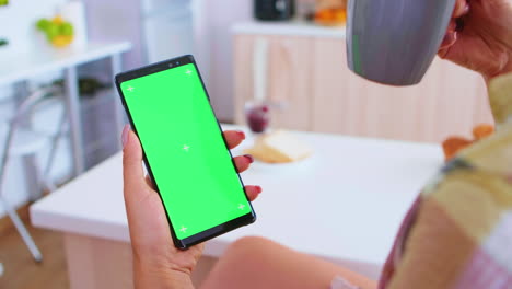 Woman-holding-portable-phone-with-green-screen