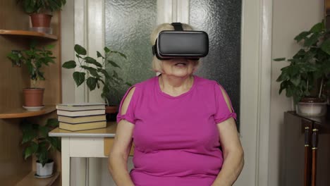 Frightened-grandmother-woman-removes-VR-goggles-while-playing-scary-games,-shows-emotion-of-surprise