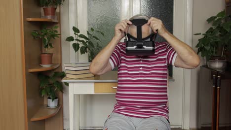 Senior-grandfather-putting-on-virtual-headset-glasses-and-watching-3d-video-in-360-vr-helmet-at-home