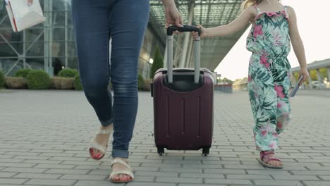 Mother-and-daughter-walking-from-airport.-Woman-carrying-suitcase-bag.-Child-and-mom-after-vacation