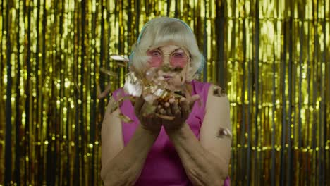 Happy-senior-old-woman-laughing,-blowing-confetti-glitters,-celebrating-birthday,-winning-lottery