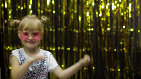 Child-kid-dancing,-celebrating-victory,-fooling-around.-Girl-posing-on-background-with-foil-curtain