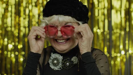 Lovely-mature-old-woman-touching-red-sunglasses-and-winking-playfully,-flirting-and-blinking-eye