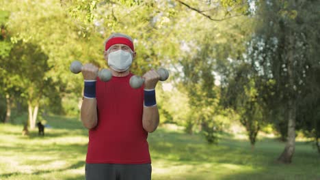 Senior-man-making-fitness-exercises-with-dumbbells-during-coronavirus-virus-pandemic-alone-in-park