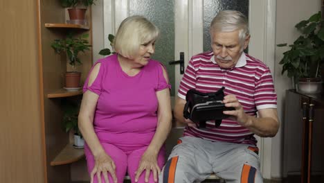 Grandfather-and-grandmother-with-VR-headset-helmet-play-games,-watch-virtual-reality-3D-360-video