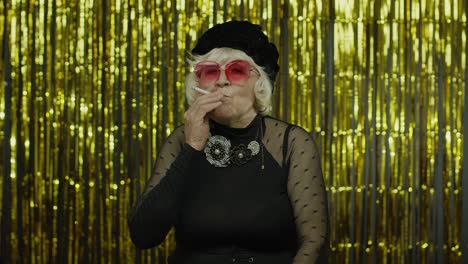 Elderly-style-mature-woman-in-fashion-black-clothes-in-sunglasses-posing,-smoke-cigarette