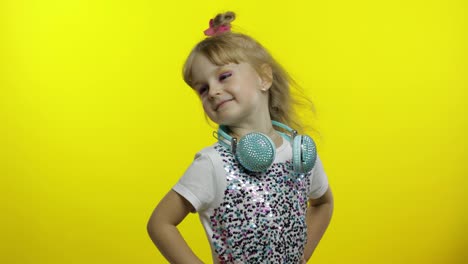 Child-with-headphones,-showing-thumb-up.-Relaxing,-enjoying,-having-hun-on-yellow-background