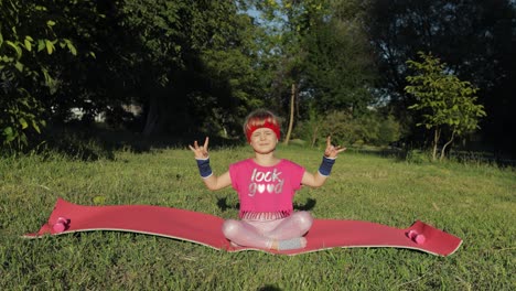 Child-sitting-on-mat-and-performing-yoga-meditation-outdoors-in-park.-Girl-doing-yoga-exercises