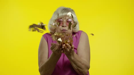 Happy-senior-old-woman-laughing,-blowing-confetti-glitters,-celebrating-birthday,-winning-lottery