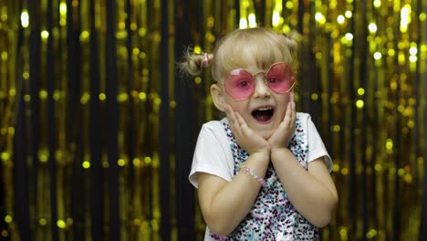 Child-dancing,-show-amazement,-fooling-around,-smiling.-Girl-posing-on-background-with-foil-curtain