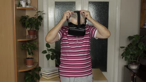 Der-ältere-Großvater-Setzt-Eine-Virtuelle-Headset-Brille-Auf-Und-Schaut-Sich-Zu-Hause-3D-Videos-Im-360-VR-Helm-An