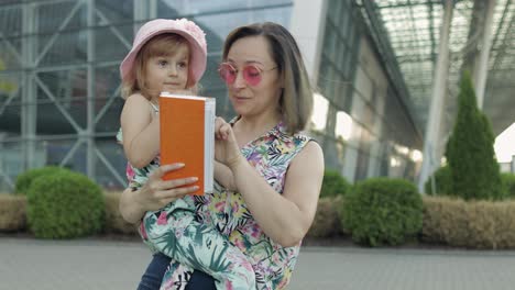 Mother-and-daughter-near-airport.-Woman-hold-passports-and-tickets-in-hand.-Child-and-mom-vacation
