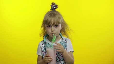 Stylish-child-drinking-milk-cocktail-through-straw-and-showing-thumb-up.-Cold-milkshake-drink