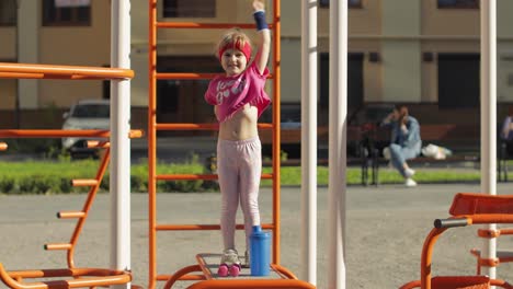 Young-cute-child-girl-in-sportswear-making-fitness-gymnast-exercises-on-playground.-Workout-for-kids