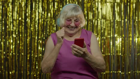 Elegante-Y-Feliz-Anciana-Sosteniendo-Un-Teléfono-Celular,-Escuchando-Música-Con-Auriculares-Y-Bailando