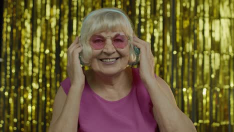 Senior-old-woman-dances,-listens-music-on-headphones.-Having-fun,-smiling,-showning-thumb-up