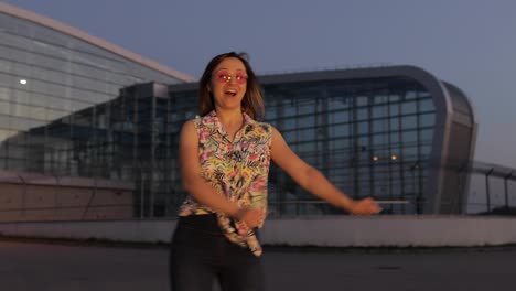 Happy-woman-tourist-dancing-floss-meme-dance-joyfully,-celebrating-success,-enjoying-music.-Sunset