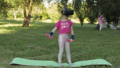 Athletic-child-girl-in-VR-headset-helmet-making-fitness-workout-exercises-with-dumbbells-in-park