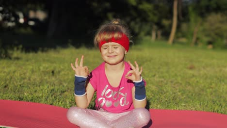 Kind-Sitzt-Auf-Matte-Und-Führt-Yoga-Meditation-Im-Freien-Im-Park-Durch.-Mädchen-Macht-Yoga-Übungen