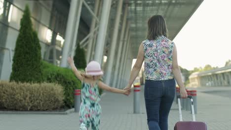 Mother-and-daughter-walking-to-airport.-Woman-carrying-suitcase-bag.-Child-and-mom-vacation.-Rear