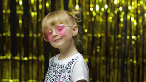 Child-smiling,-looking-at-camera,-making-fly-kiss.-Girl-posing-on-background-with-foil-curtain