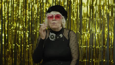 Elderly-style-mature-granny-in-fashion-black-clothes-in-sunglasses-posing,-smoke-cigarette