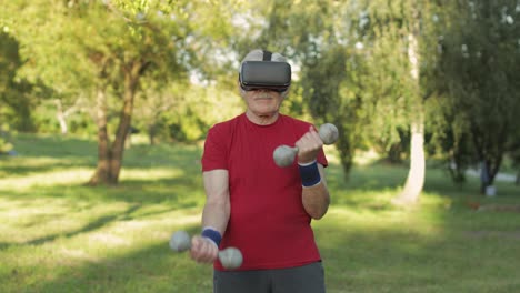 Senior-old-grandfather-man-in-VR-headset-helmet-making-fitness-exercises-with-dumbbells-outdoors