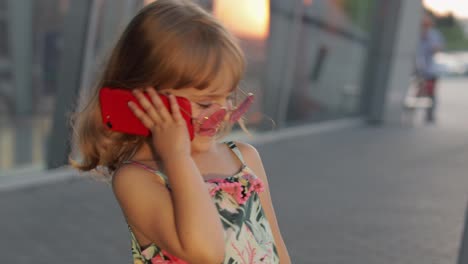 Tourist-kid-girl-wearing-stylish-sunglasses-use-phone.-Child-using-smartphone-for-call-talk.-Tourism