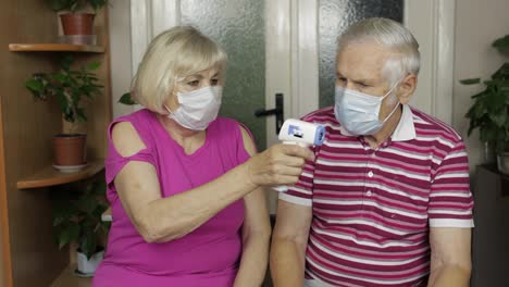 Grandfather-and-grandmother-measures-temperature-with-electronic-thermometer.-Coronavirus,-Covid-19