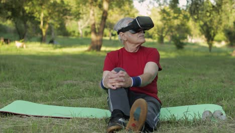 Elderly-man-in-VR-headset-helmet-sitting-on-sport-mat.-Online-sport-workout-for-senior-people