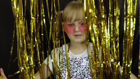 Happy-child-jumping,-playing,-fooling-around-in-shiny-foil-fringe-golden-curtain.-Little-blonde-kid