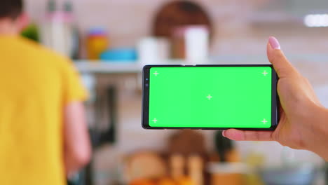 Woman-hand-holding-smartphone-with-green-screen