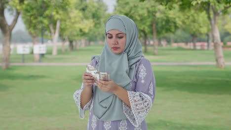 Mujer-Musulmana-Seria-Contando-Dinero-En-El-Parque