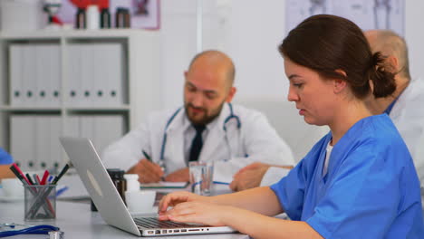 Assistent-Tippt-Auf-Laptop-Besprechungsinformationen,-Während-Ärzte-Diskutieren