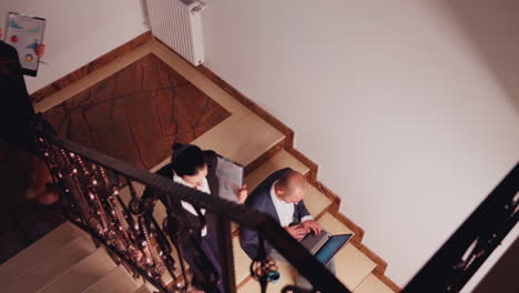 Top-view-of-busy-businessman-working-sitting-on-staircase