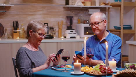 Old-couple-using-phones-in-the-kitchen