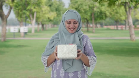 Glückliche-Muslimische-Frau,-Die-Im-Park-Ein-Geschenk-Erhält