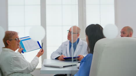 Elderly-doctor-having-medical-conference-in-hospital-meeting-room