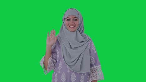 Fröhliche-Muslimische-Frau,-Die-„Hallo“-Auf-Grünem-Bildschirm-Sagt