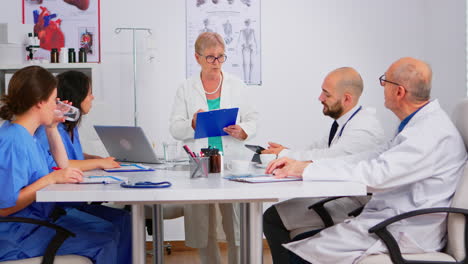 Mature-doctor-presenting-new-medical-procedures-standing-at-desk