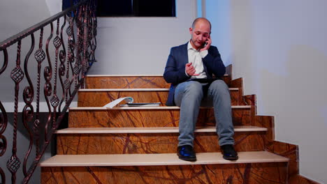 Man-talking-on-smartphone-and-checking-annual-reports-on-stairs